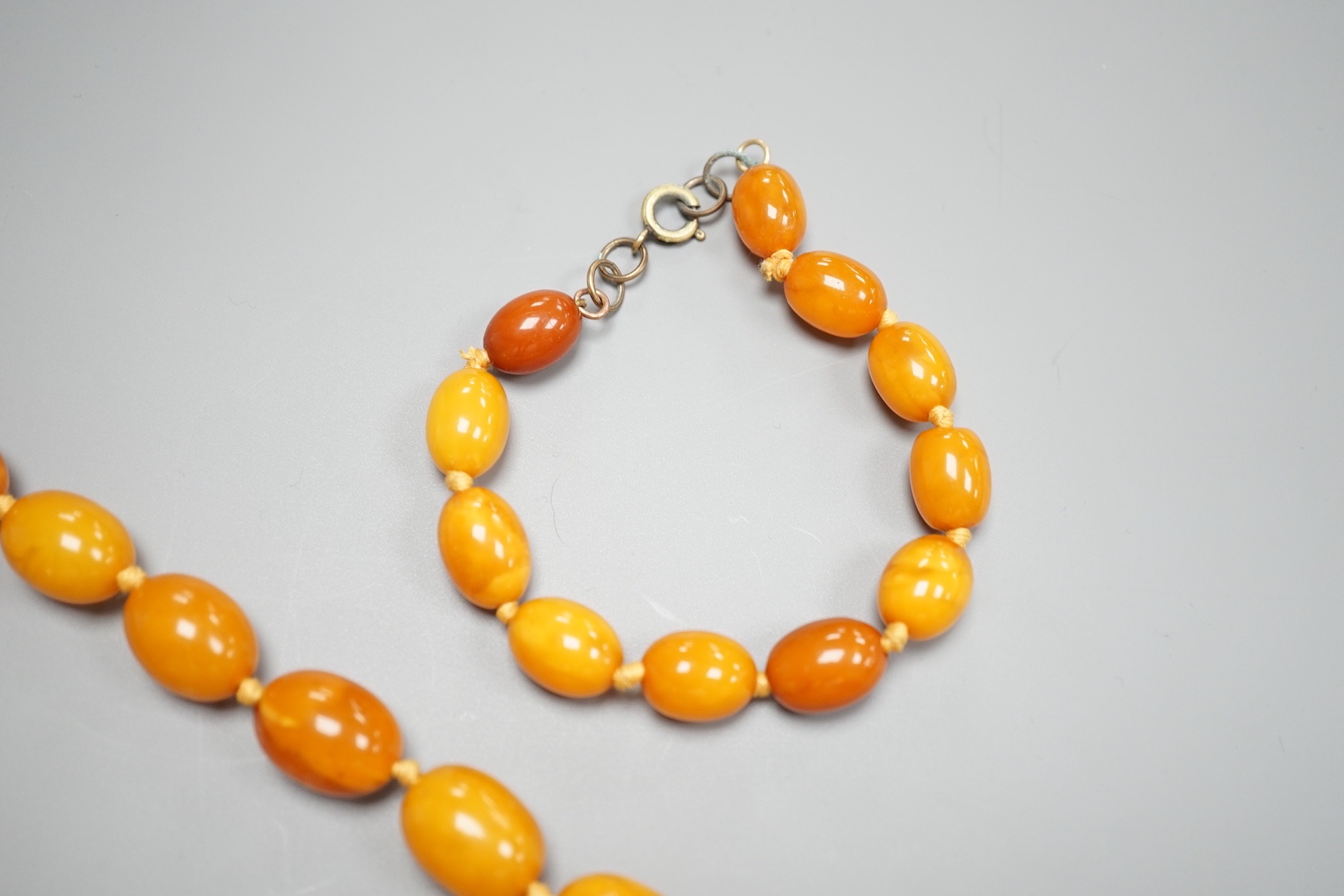 A single strand graduated oval amber bead necklace, 65cm and a similar bracelet, 18cm, gross weight 82 grams.